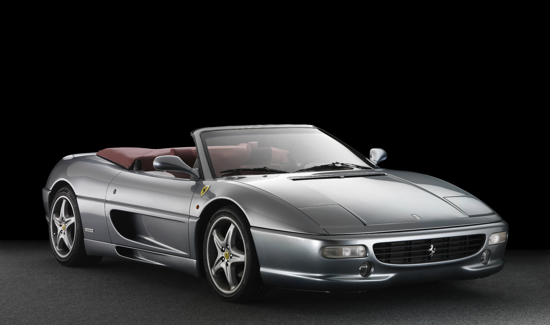 Silver Ferrari F355 Spider with red interior, top down